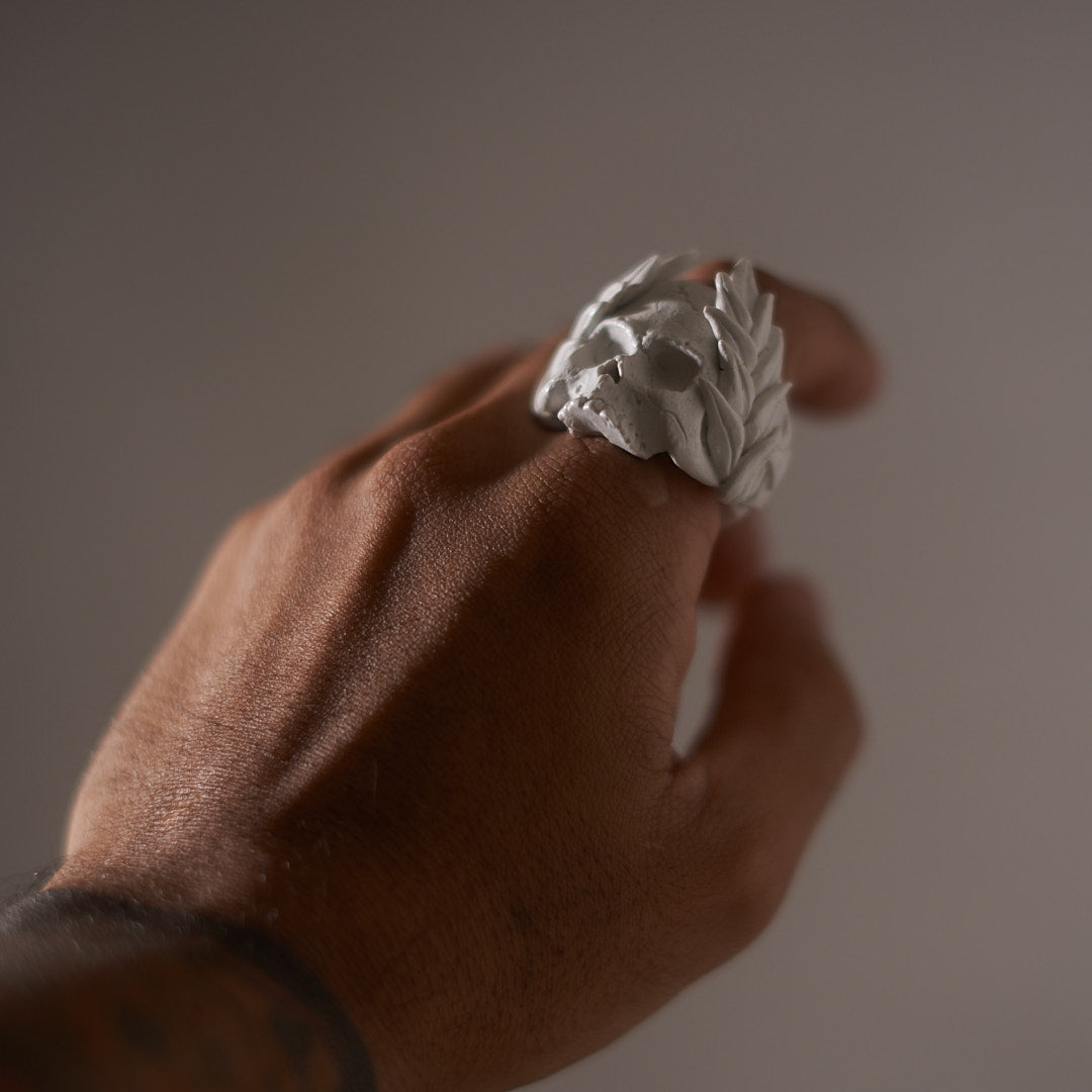 hand wearing a white gothic skull ring with crown of leaves